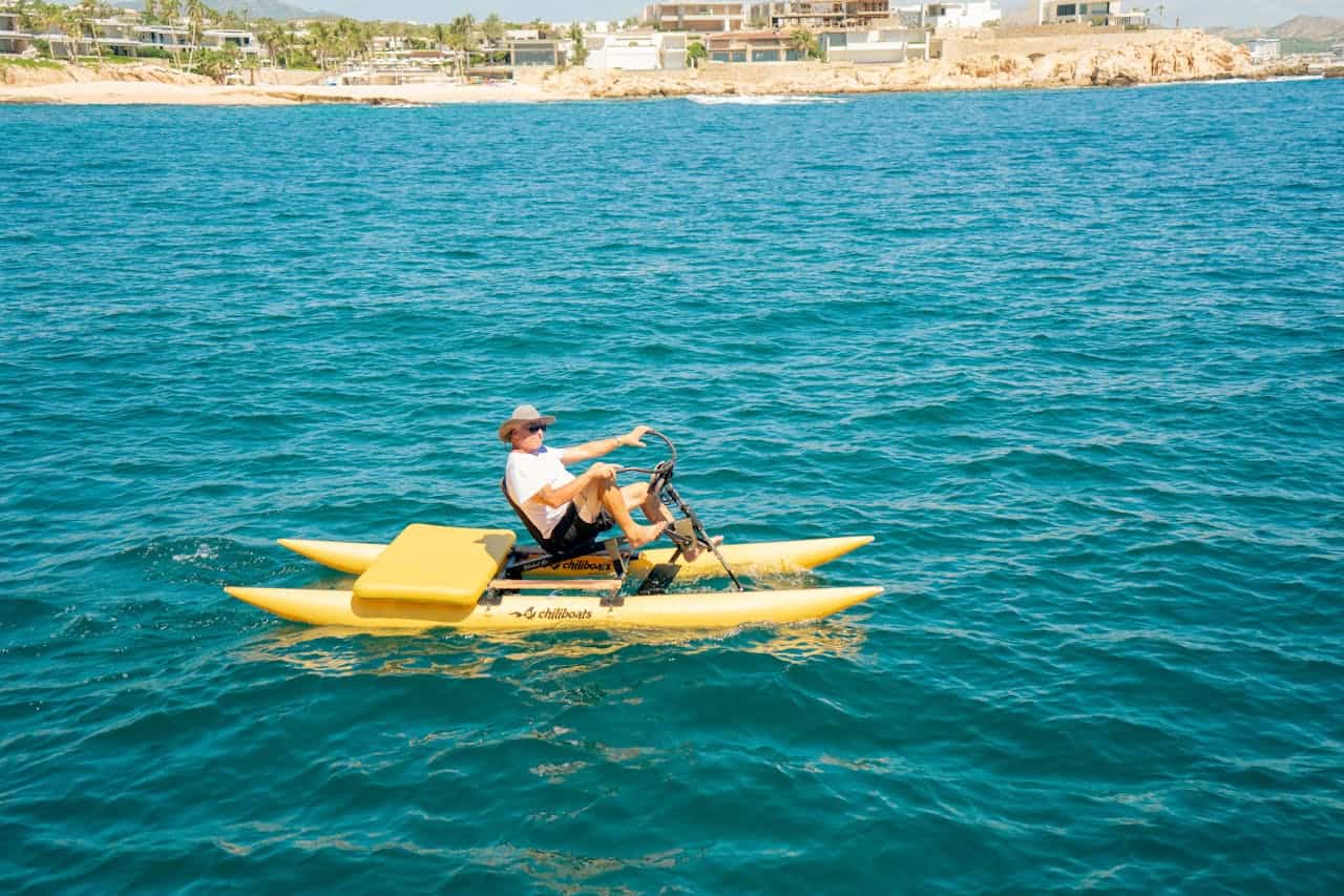 Home A man leisurely rides a yellow watercraft on the blue waters near Cabo San Lucas coastline.