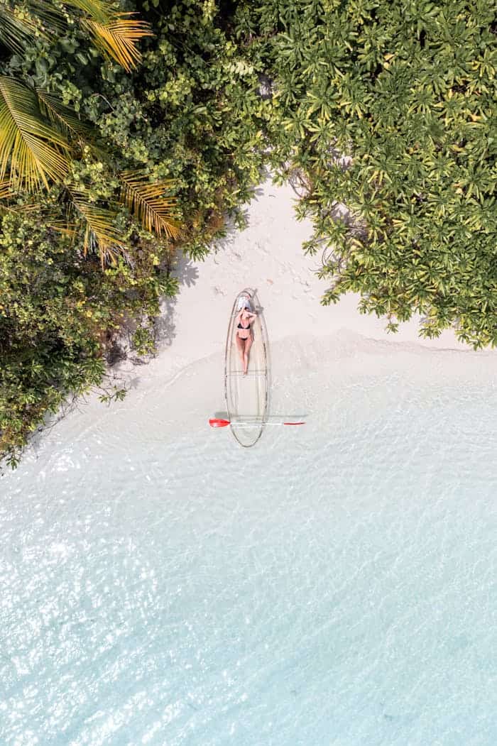 Clear kayak floating on pristine beach water in the Maldives.